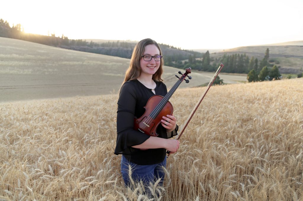 Kyra Harris in a wheat field with a violin