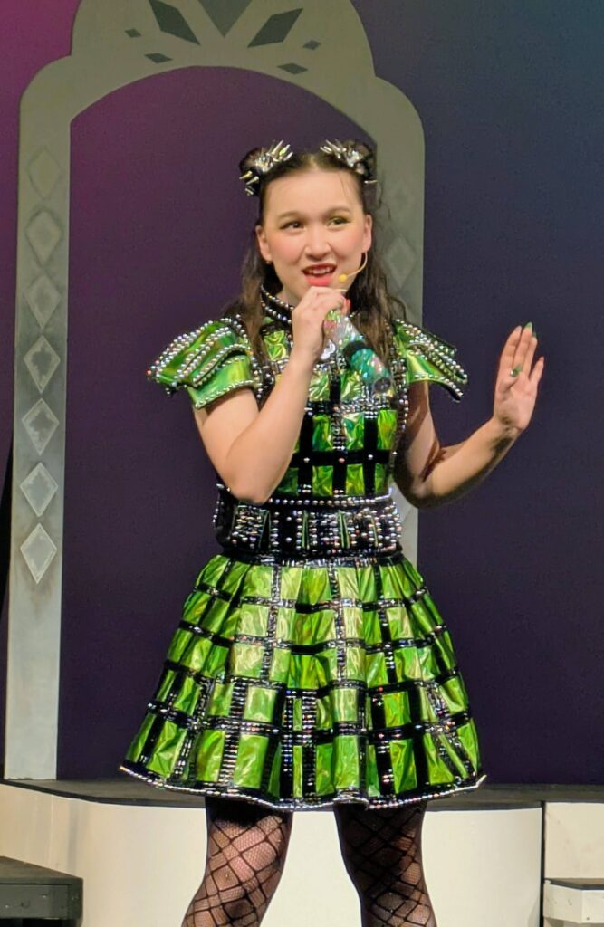 Young woman in green dress sings on stage